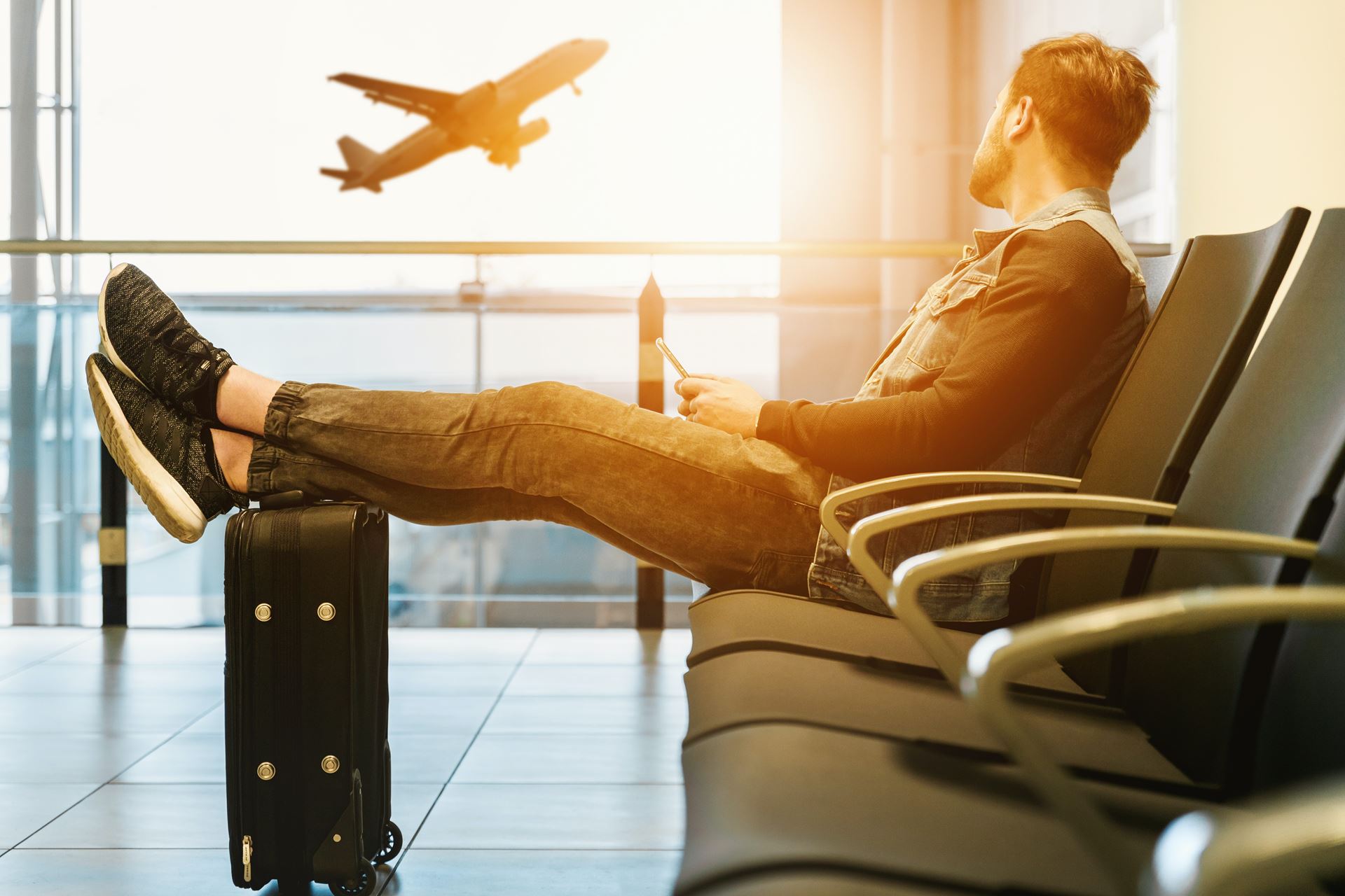 A man in an airport looking at a plane out the window.